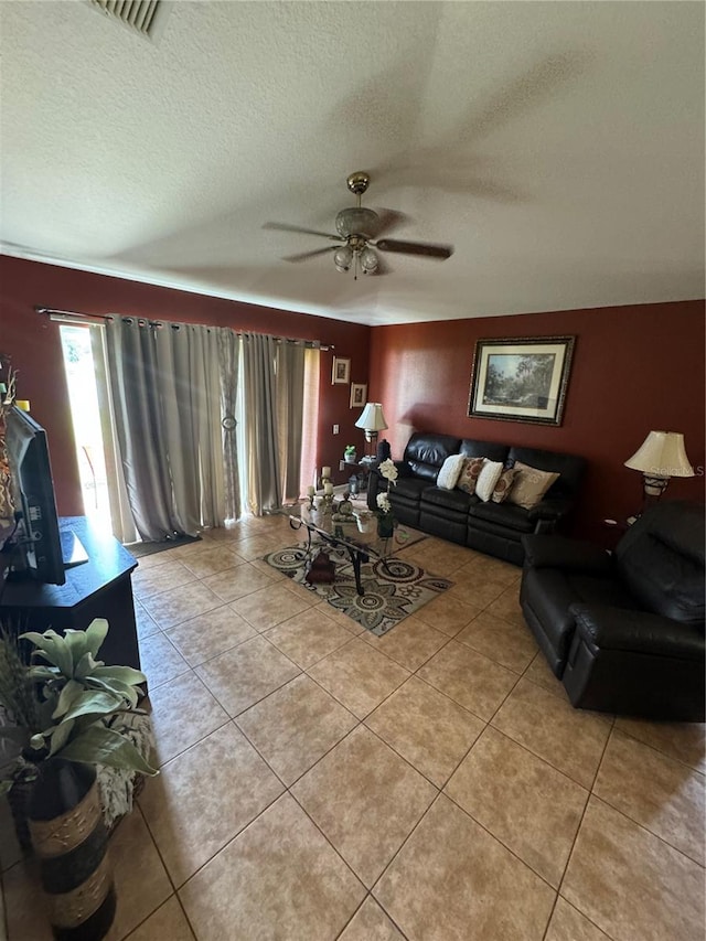 living room with ceiling fan, light tile patterned floors, and a textured ceiling