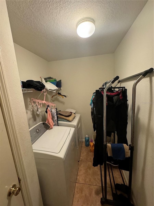 laundry room with washing machine and clothes dryer, a textured ceiling, and light tile patterned floors