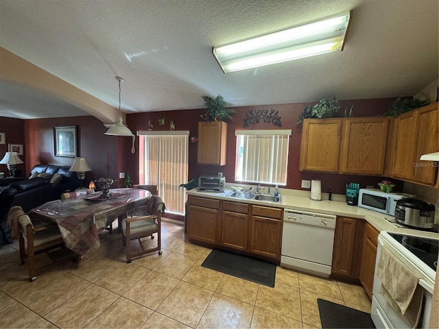 kitchen with hanging light fixtures, white appliances, light tile patterned floors, a textured ceiling, and sink