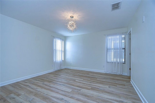 empty room with light hardwood / wood-style floors and a notable chandelier