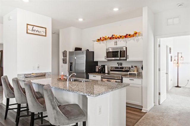 kitchen featuring kitchen peninsula, a breakfast bar, stainless steel appliances, and white cabinets