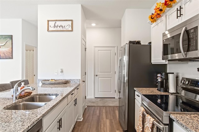 kitchen with dark hardwood / wood-style flooring, sink, light stone countertops, appliances with stainless steel finishes, and white cabinetry