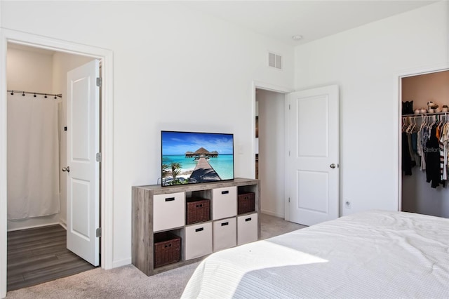 bedroom featuring a closet, a walk in closet, ensuite bathroom, and light wood-type flooring