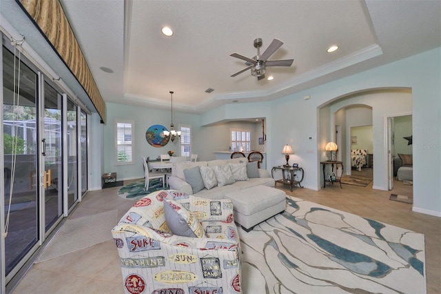 carpeted living room featuring a tray ceiling, crown molding, and ceiling fan with notable chandelier