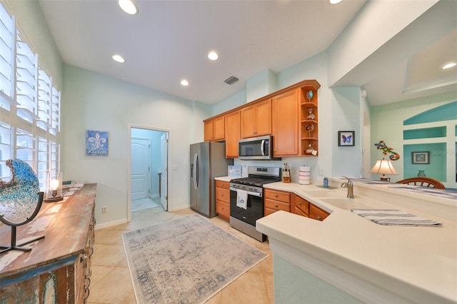 kitchen featuring sink, kitchen peninsula, stainless steel appliances, and light tile patterned floors