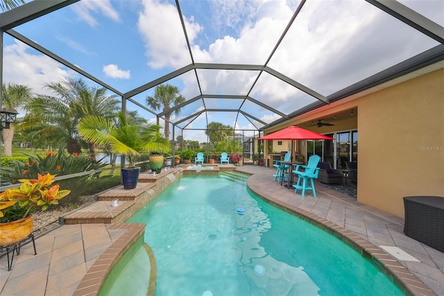 view of swimming pool with a lanai, pool water feature, ceiling fan, and a patio