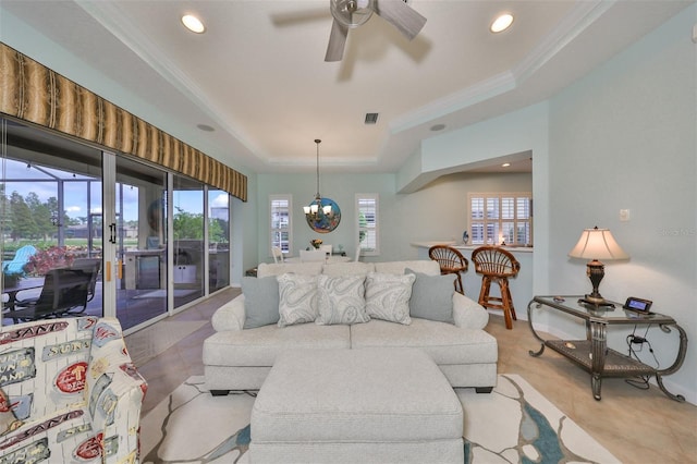 living room with ceiling fan with notable chandelier, a tray ceiling, and crown molding