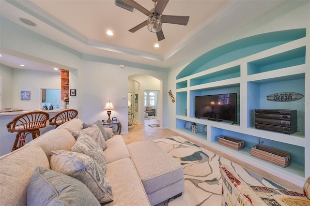 tiled living room with a raised ceiling, ceiling fan, and built in features