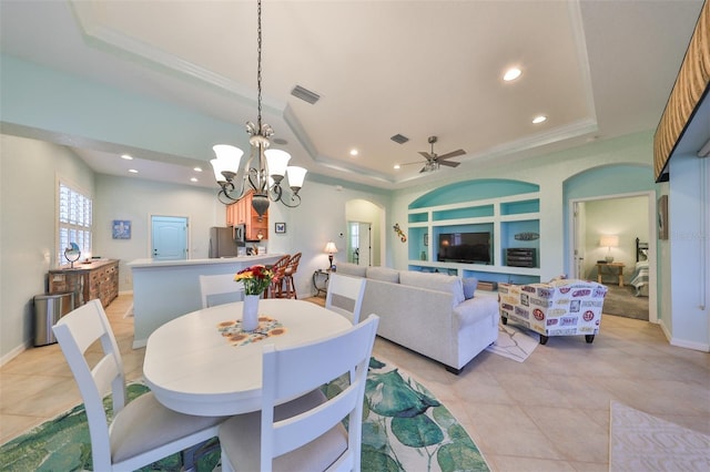 dining room with a raised ceiling, crown molding, light tile patterned floors, and ceiling fan with notable chandelier