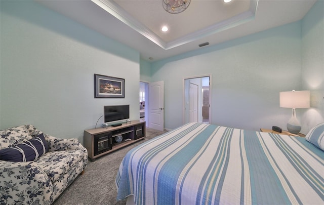 carpeted bedroom featuring a tray ceiling and ensuite bath