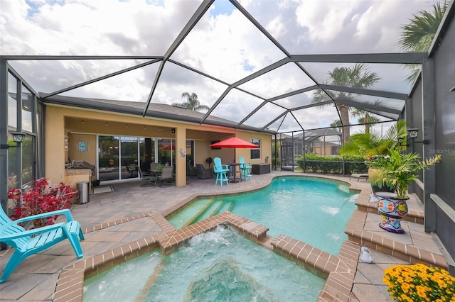 view of swimming pool featuring pool water feature, glass enclosure, a patio area, and an in ground hot tub