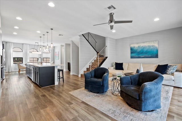 living room with ceiling fan, light hardwood / wood-style flooring, and sink