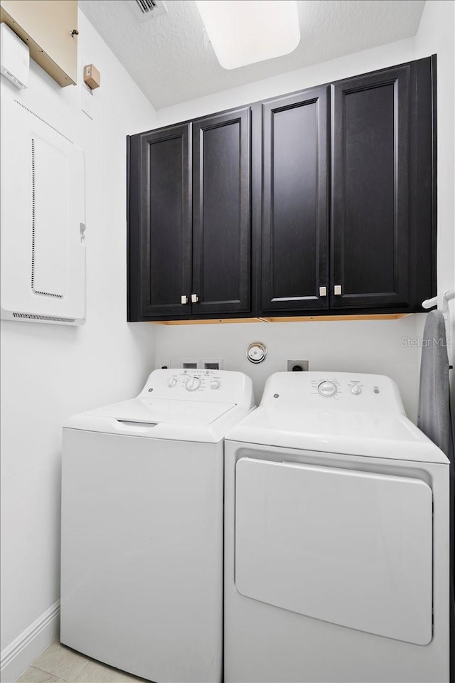 laundry area featuring cabinets, light tile patterned floors, and washer and clothes dryer