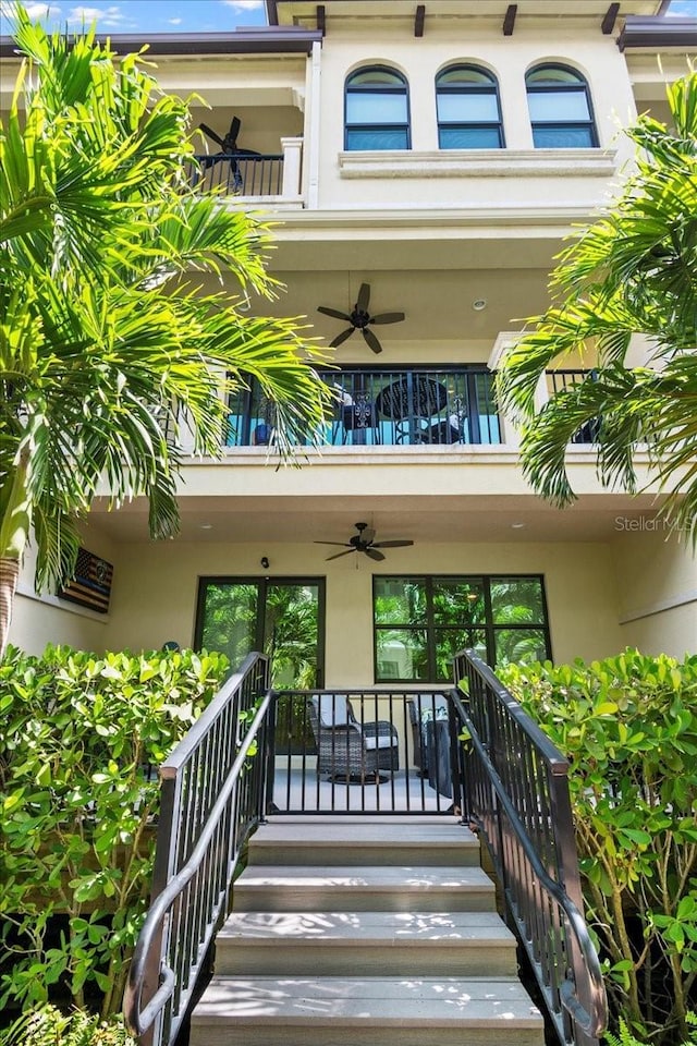 view of exterior entry with a balcony, french doors, and ceiling fan