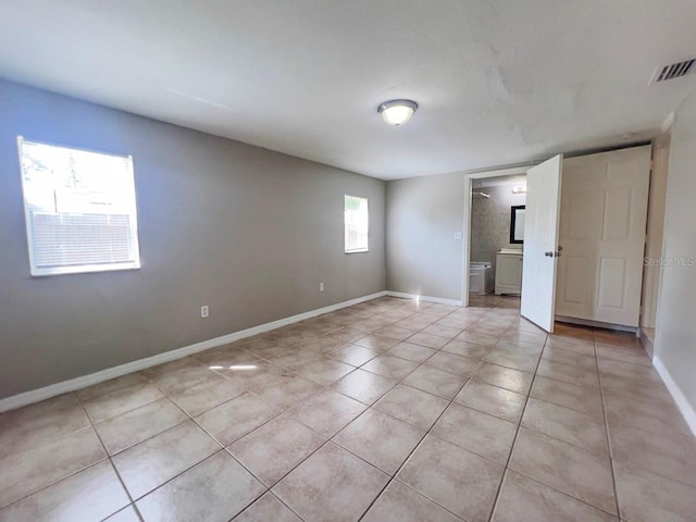 interior space with ensuite bath and light tile patterned floors