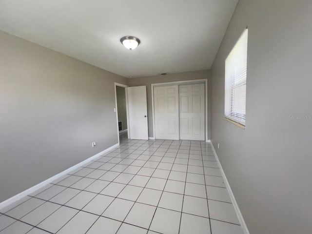 unfurnished bedroom with light tile patterned floors and a closet