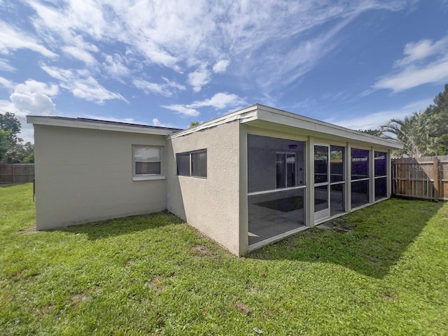 rear view of house with a lawn and a sunroom