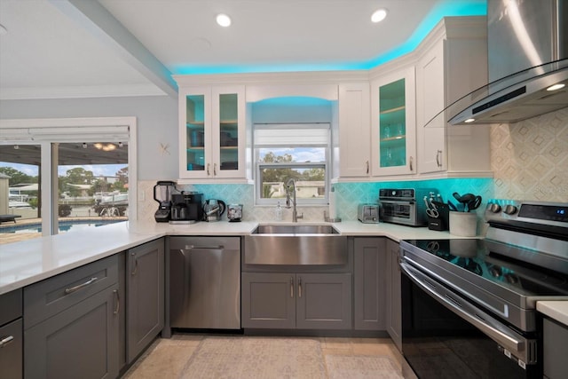 kitchen featuring tasteful backsplash, sink, white cabinets, wall chimney range hood, and appliances with stainless steel finishes