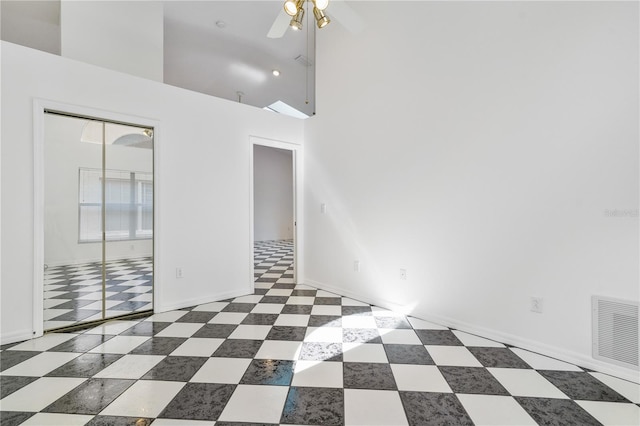 unfurnished room featuring ceiling fan and a high ceiling