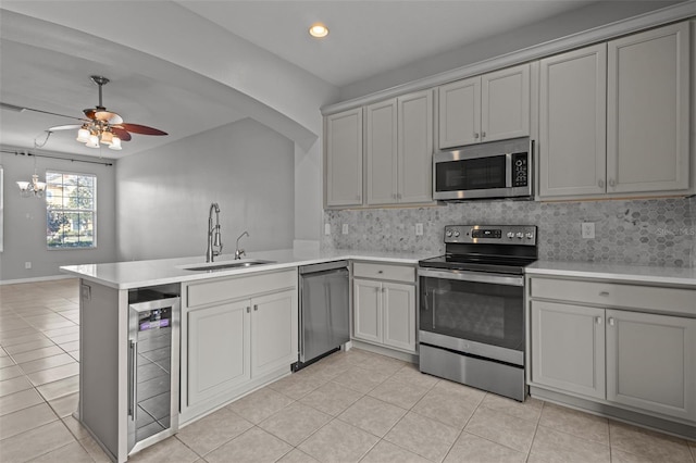 kitchen featuring wine cooler, sink, kitchen peninsula, appliances with stainless steel finishes, and ceiling fan with notable chandelier