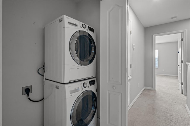 laundry area featuring light colored carpet and stacked washer / dryer