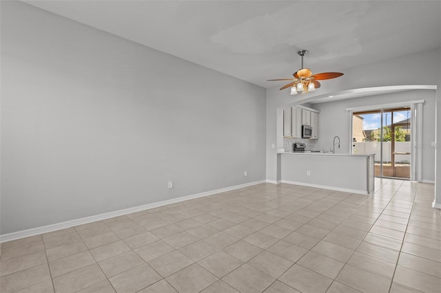 unfurnished living room with light tile patterned flooring, sink, and ceiling fan