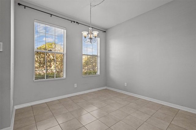 empty room with a notable chandelier and light tile patterned flooring