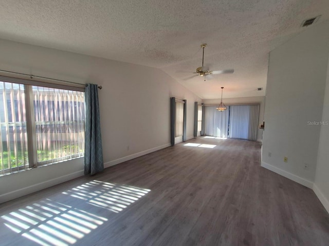 empty room with dark hardwood / wood-style floors, ceiling fan, lofted ceiling, and a textured ceiling