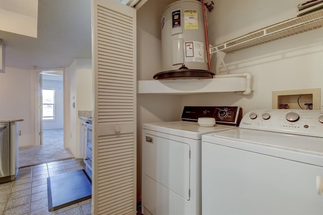 washroom with light tile patterned floors, washing machine and dryer, and water heater