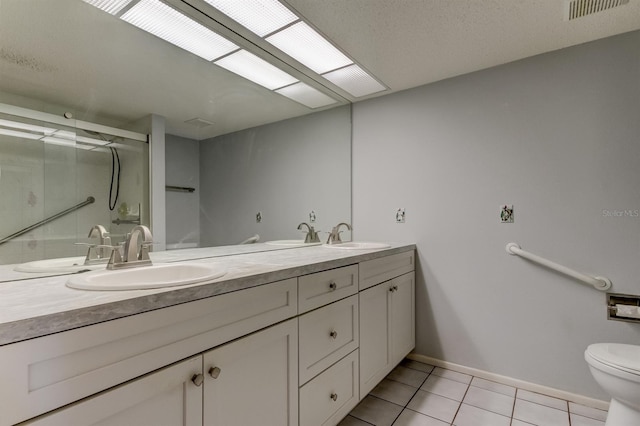 bathroom featuring tile patterned flooring, vanity, toilet, and a shower with shower door