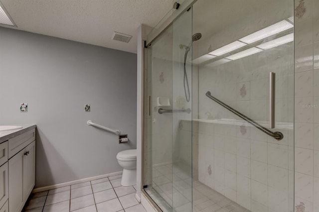 bathroom with tile patterned flooring, vanity, a shower with shower door, and toilet