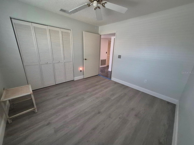 unfurnished bedroom featuring a textured ceiling, a closet, hardwood / wood-style flooring, and ceiling fan