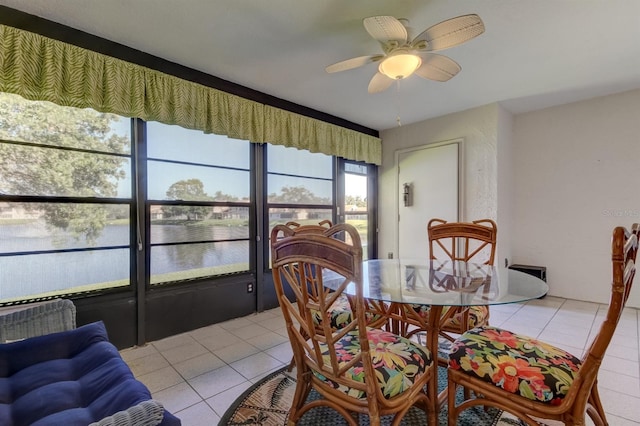 dining area with light tile patterned floors, a water view, and ceiling fan