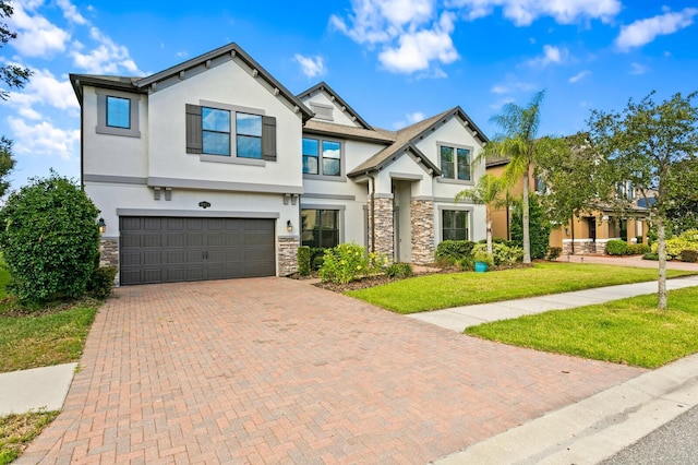 view of front facade with stone siding, decorative driveway, an attached garage, a front yard, and stucco siding