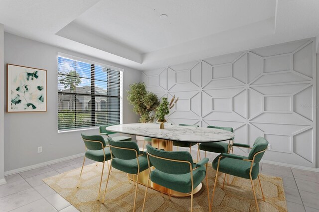 dining area featuring light tile patterned floors and a raised ceiling