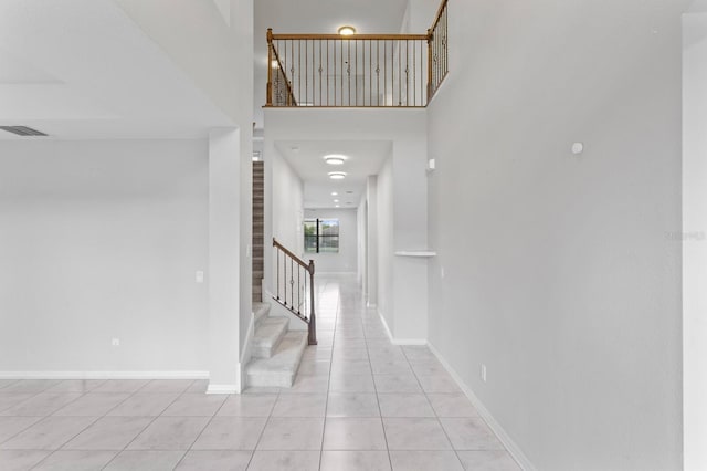 interior space with visible vents, baseboards, a towering ceiling, stairway, and light tile patterned floors