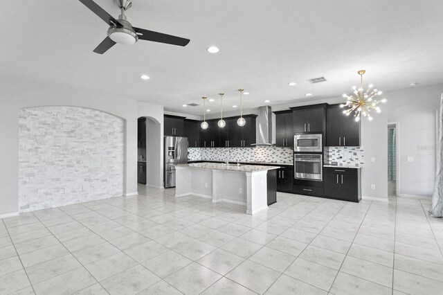 kitchen with stainless steel appliances, backsplash, visible vents, wall chimney range hood, and dark cabinets