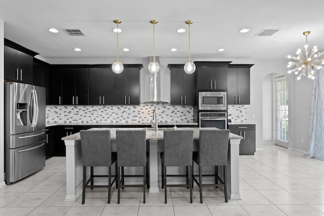 kitchen featuring visible vents, wall chimney exhaust hood, dark cabinetry, and stainless steel appliances