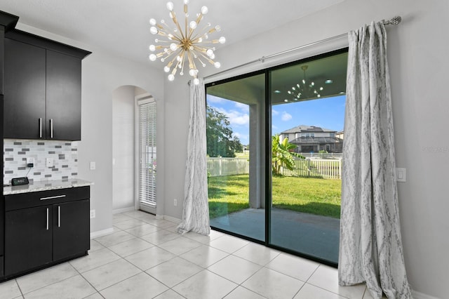 doorway to outside featuring an inviting chandelier and light tile patterned flooring