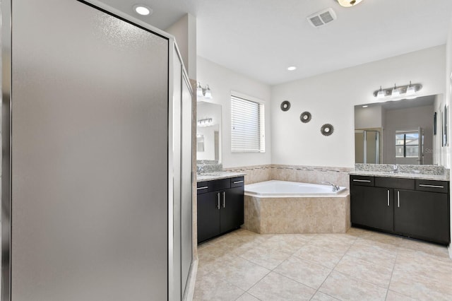 bathroom featuring tile patterned flooring, a shower stall, a sink, a garden tub, and visible vents