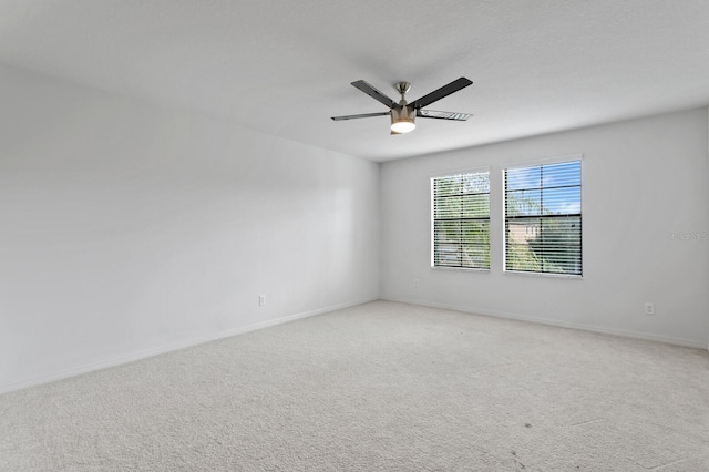 empty room featuring light colored carpet, ceiling fan, and baseboards