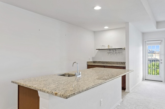 kitchen featuring light colored carpet, recessed lighting, baseboards, a sink, and light stone counters