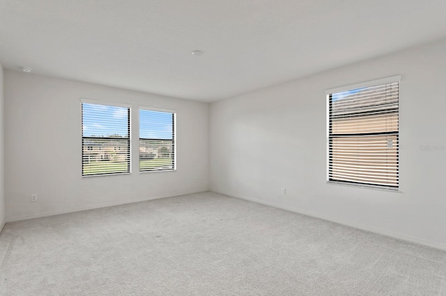 unfurnished room featuring light carpet and baseboards