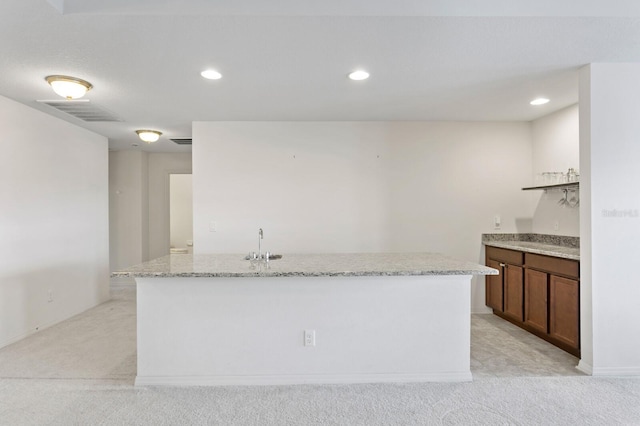kitchen featuring visible vents, recessed lighting, a center island with sink, light carpet, and a sink