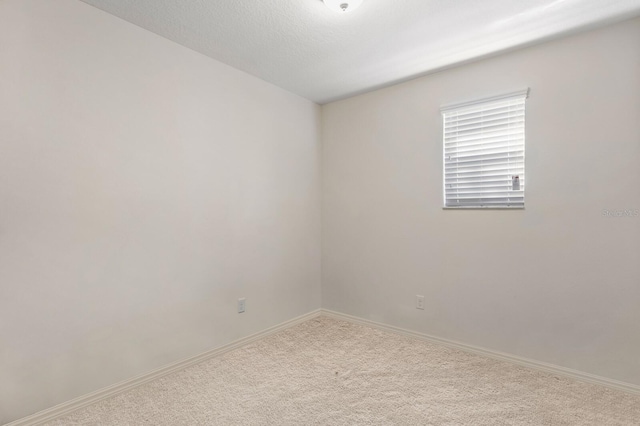 spare room featuring carpet flooring, baseboards, and a textured ceiling