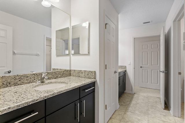 full bath featuring tile patterned flooring, vanity, baseboards, and visible vents
