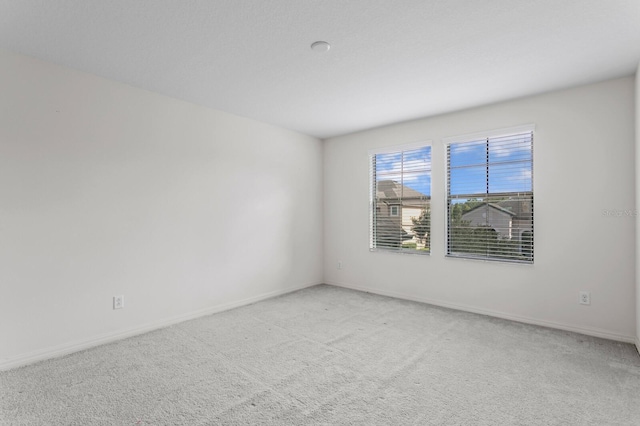 empty room with light colored carpet and baseboards