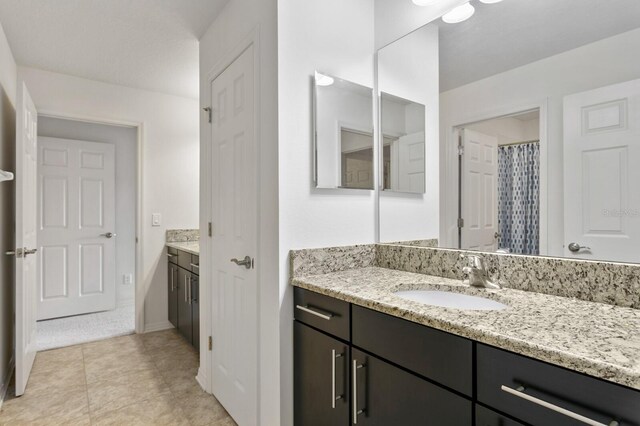 full bath with tile patterned flooring, vanity, and baseboards