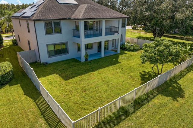 back of property with a balcony, a fenced backyard, a lawn, and stucco siding