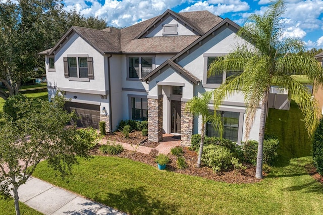 view of front of home featuring stucco siding, a garage, stone siding, and a front lawn